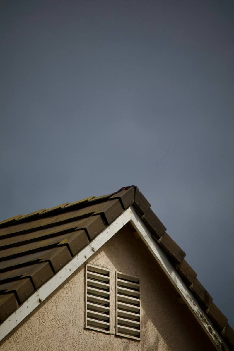 Residential roof peak silhouetted against a stormy sky