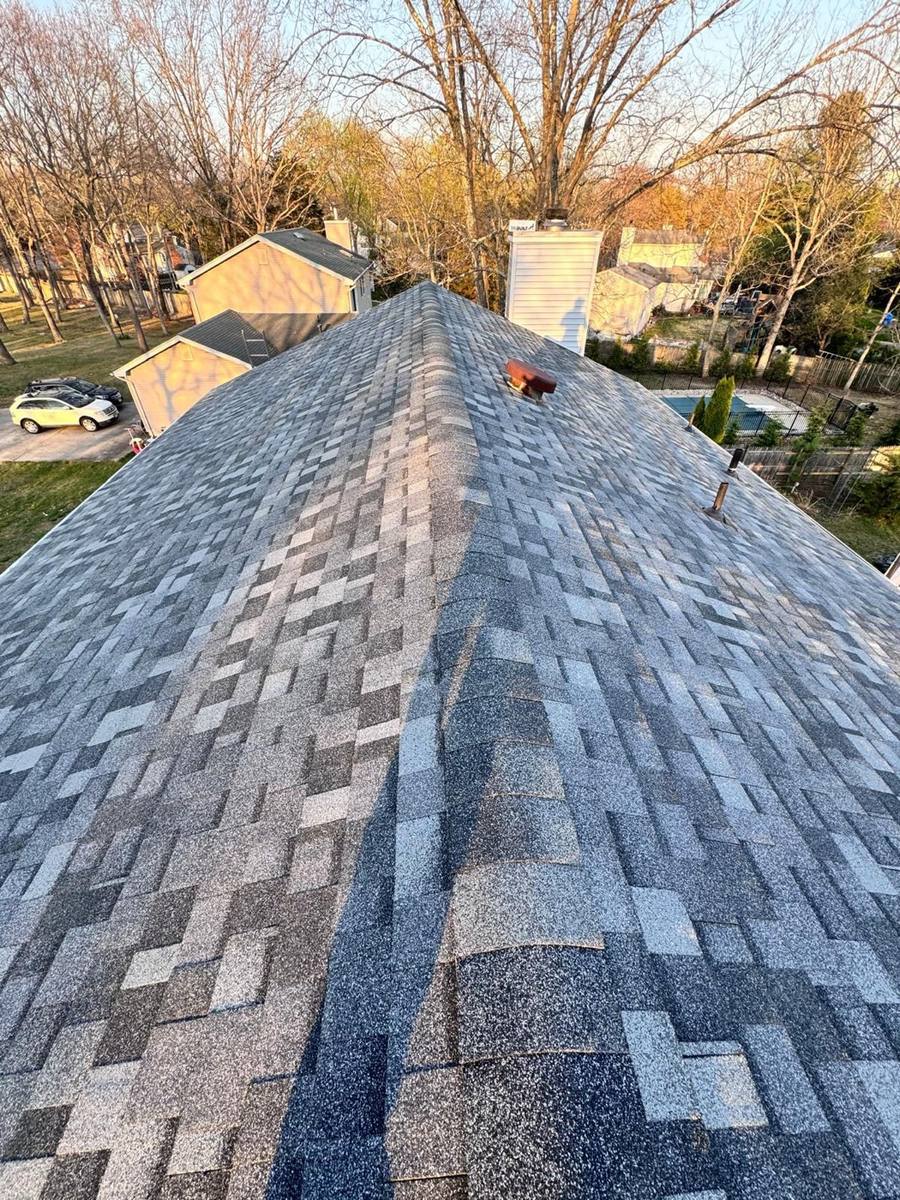 Freshly installed grey shingles with a skylight  - crew finishing the job